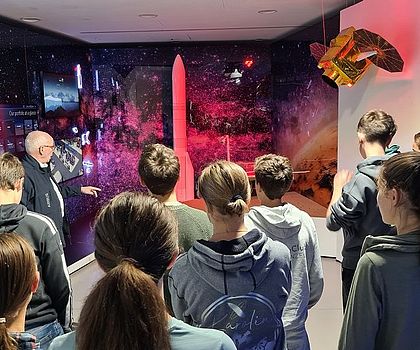 Eine Gruppe von Jugendlichen bekommt Produkte von Airbus erklärt.
