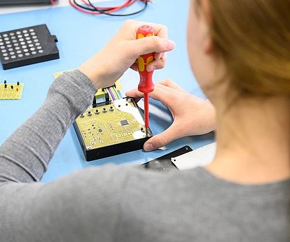 Ein Mädchen schraubt dasGehäuse des Werkstücks zusammen