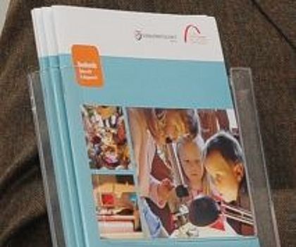 Auf dem Foto sind mehrere Broschüren zum Projekt Es funktioniert?! zu sehen.  Ein paar dieser Broschüren stehen in einem Flyerständer, einige liegen als Stapel davor. Auf dem Titelblatt sind projektspezifische Fotos zu sehen und das orangene Tezba-Logo.