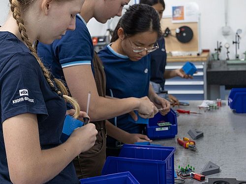 Mädchen für Technik-Camp bei Knorr Bremse Eine Gruppe von Mädchen steht an der Werkbank und montiert das Werkstück zusammen