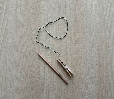 Auf einem Tisch liegen verschiedenen Materialien (Draht, Bleistift, Wäscheklammer)