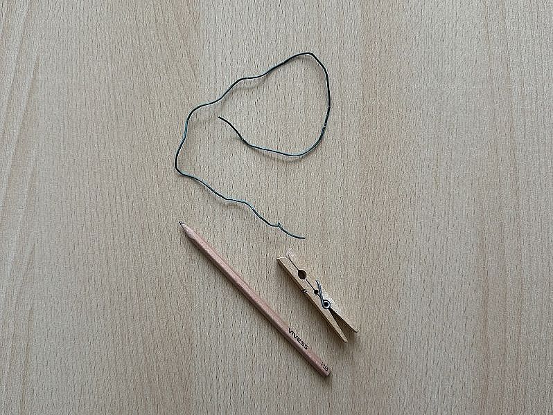 Auf einem Tisch liegen verschiedenen Materialien (Draht, Bleistift, Wäscheklammer)
