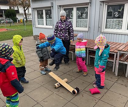 Auf dem Foto sind Kinder zu sehen, die ein Katapult aufgebaut haben und ausprobieren