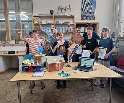 Jubelnde Schüler hinter einer gebastelten Raumstation