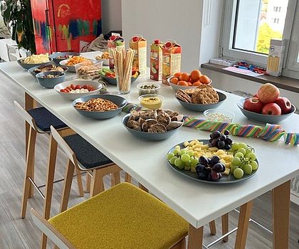 Man sieht den Stehtisch mit verschiedenen Snacks wie Käse, Trauben, Chips, Dips. 