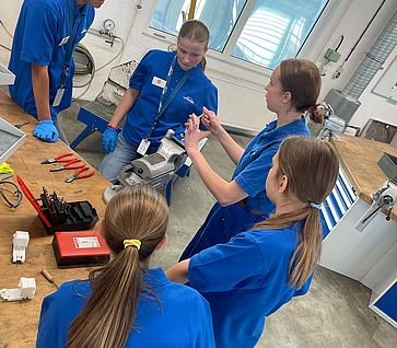 Mädchen für Technik-Camp bei Linde in Tacherting 4 Mädchen stehen an der WErkbank. Daneben steht eine Auszubildende, welche die genauen Arbeitsschritte erklärt