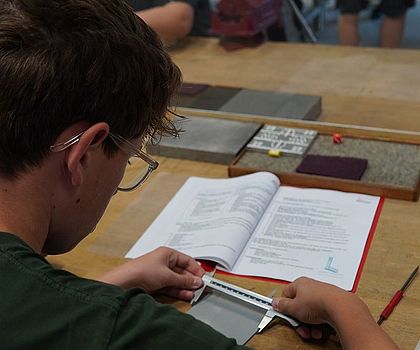 Ein Junge misst die genaue Länge des Materials ab