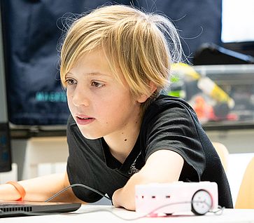 Besuch im DLR_School_Lab Das Foto zeigt einen Jungen mit einem Thymio-Roboter