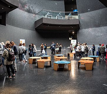 Marktplatz der Idee auf der Tagung zur Frühen MINT-Bildung Großer, runder, offener Raum, in dem Menschen zum Austausch kommen