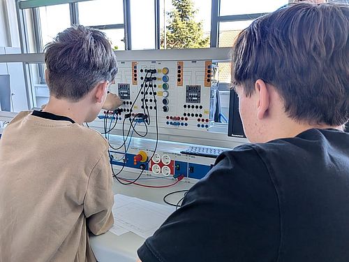 Zwei Jungen sitzen vor einem Schaltkreis und lernen dessen Aufbau