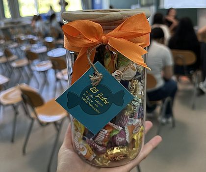 Eine Hand hält eine Bonbonglas in die Luft