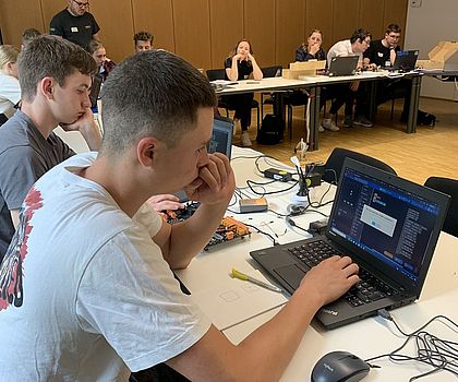 Ein Junge sitzt vor einem Laptop und programmiert