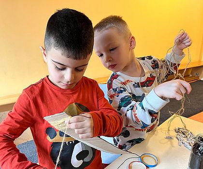 Auf dem Foto sind Kinder zu sehen, die mit Nadel und Faden nähen.