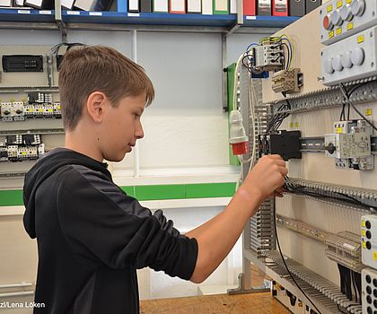 ein Jugendlicher bestückt einen Schaltschrank