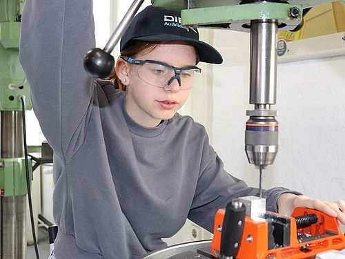 Mädchen für Technik-Camp bei Diehl Ein Mädchen steht vor einer Standbohrmaschine und bohrt Löcher in einen Metallwürfel