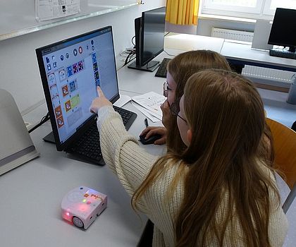 2 Mädchen sitzen vor einem Laptop und programmieren mit Hilfe von Scratch
