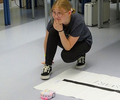 ein Mädchen kniet an der Startlinie, davor befindet sich der Thymio-Radroboter
