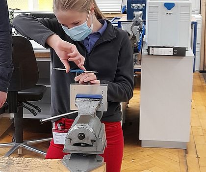 Ein Mädchen mit blonden Haaren schraubt das Gewinde in das Bauteil.