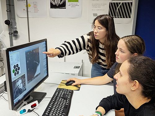 Forscherinnen-Camp in Infineon und OTH Drei Mädchen sitzen an einem Tisch. Vor Ihnen steht ein Bildschirm. Auf dem Bildschirm sieht man Zellen einer Pflanze
