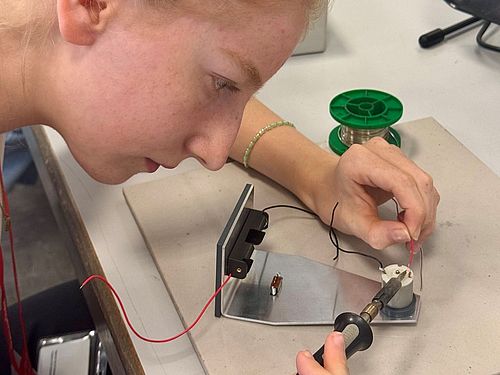 Eine Teilnehmerin des Mädchen für Technik-Camps bei ZF in Schweinfurt konzentriert sich beim Löten eines elektronischen Bauteils. Sie führt den Lötkolben präzise an eine Verbindung.