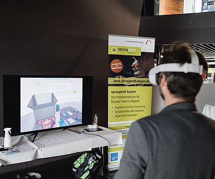 ein Mann mit VR-Brille vor einem Bildschirm