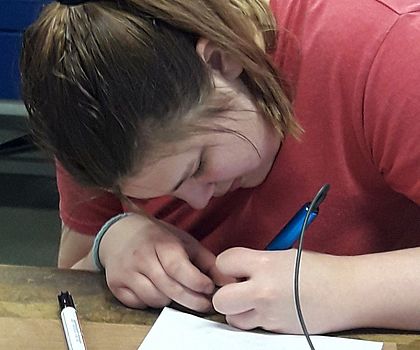 Ein Mädchen malt mit einem Kugelschreiber ein Logo.