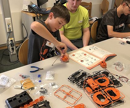 Die Teilnehmer sitzen am Tisch und bauen das Werkstück zusammen