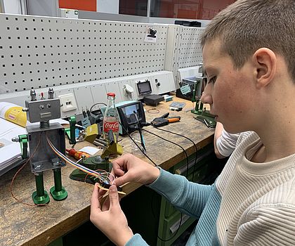 Man sieht einen Jungen, der gerade seinen Roboter fertig baut. 