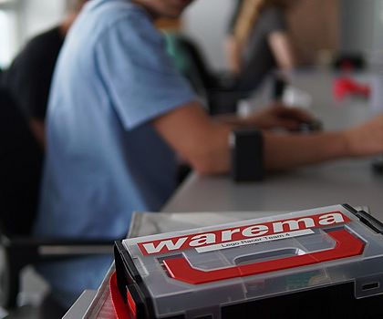 Ein Junge sitzt am Tisch. Vor ihm liegt eine Box. Auf dieser steht WAREMA