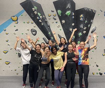 Eine Gruppe von jubelnden Mädchen vor einer Boulderwand.