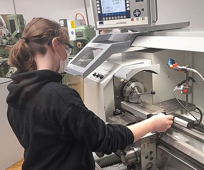 Ein Mädchen fräst die Kanten ihres Metallwürfels
