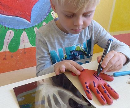 ein Junge zeichnet den Knochenaufbau einer Hand nach auf einer Gummihand